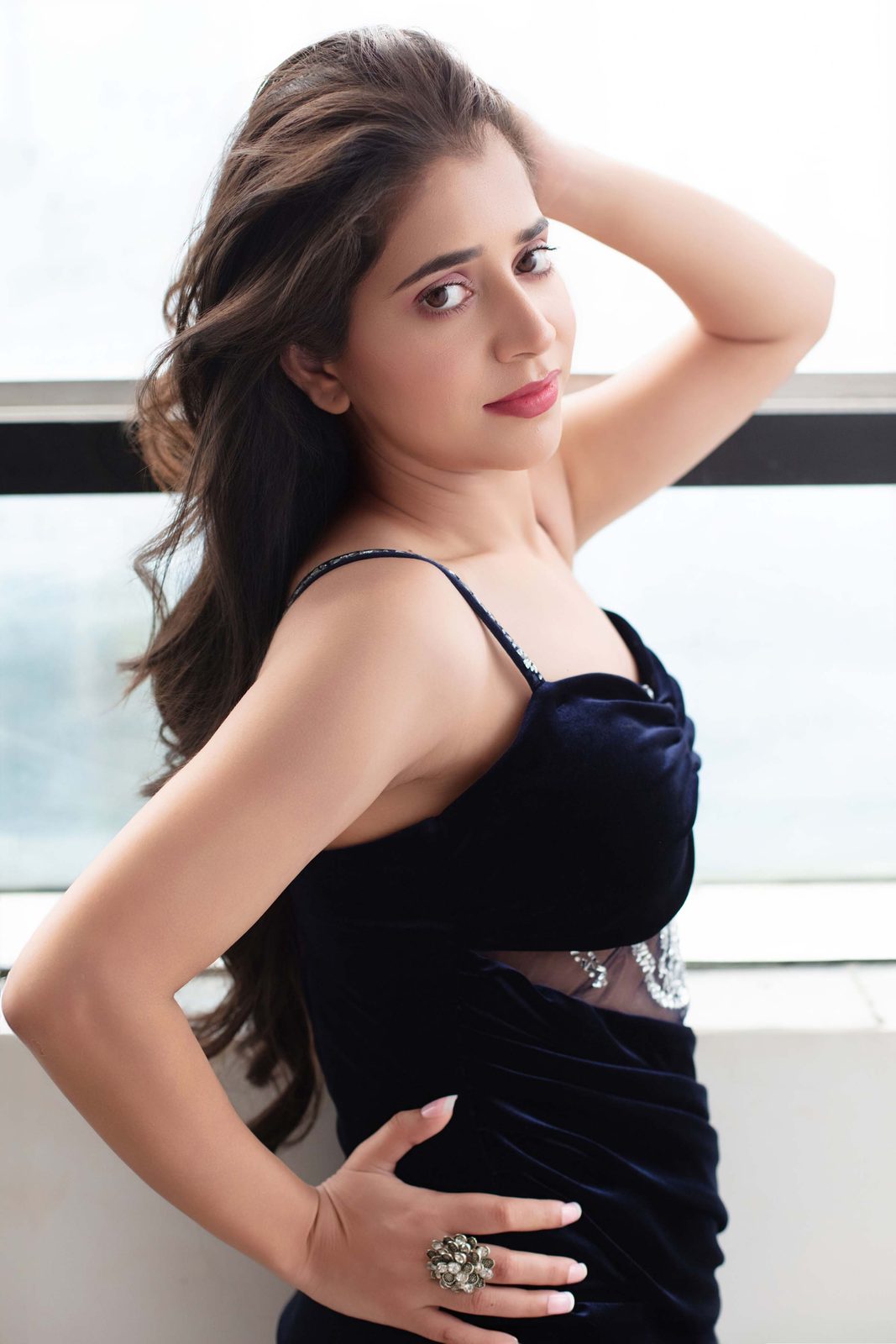 Neeru Sharma in a navy velvet gown by a window